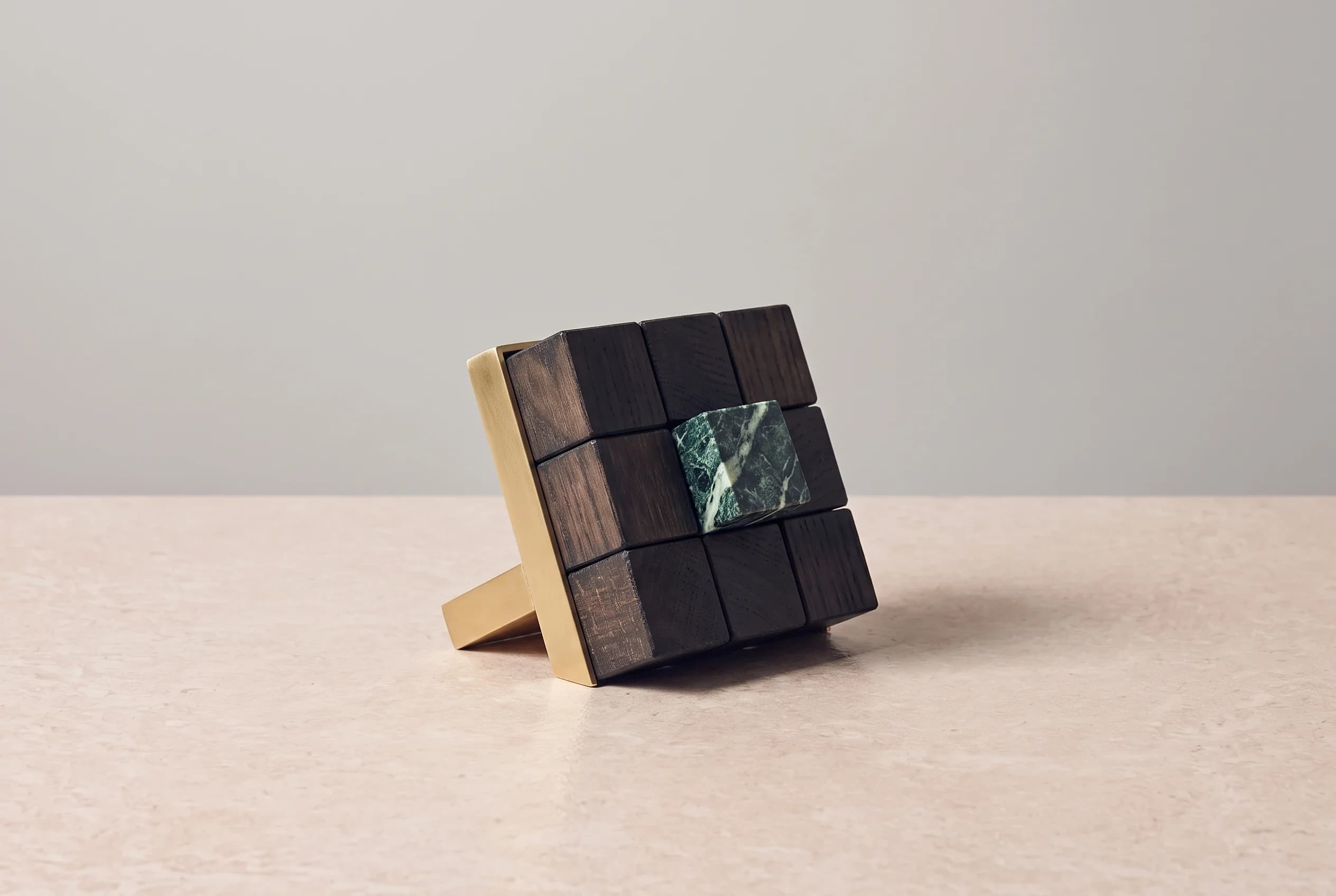 A row of dark oak calendar blocks on beige travertine, one block in green marble turned apart from the rest.